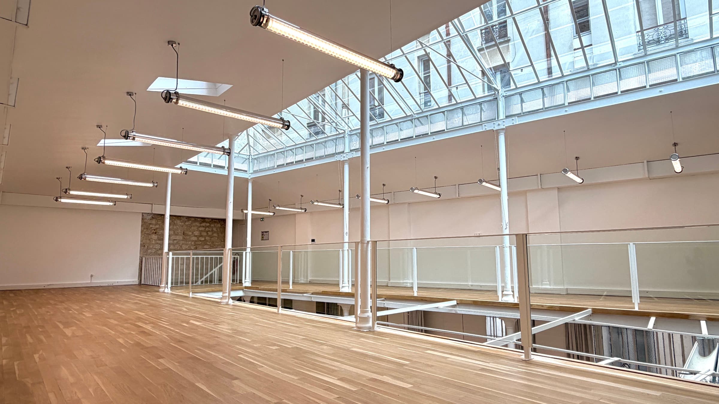 Coursive desservant les bureaux le long de la trémie, garde-corps en verre et mur en pierre