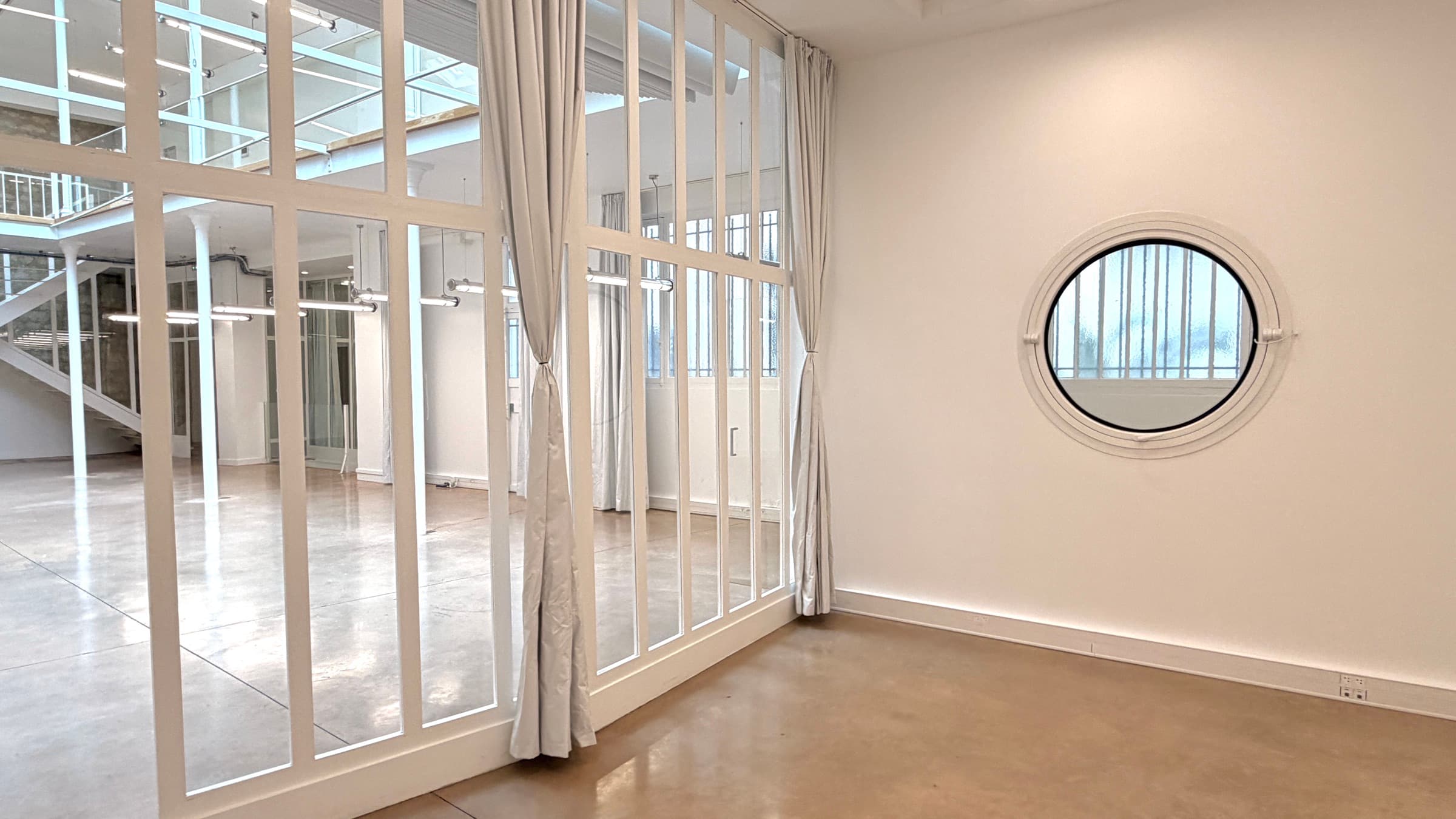 Bureau avec hublot et verrière intérieure ouvrant sur le plateau, l'escalier et le mur en pierre