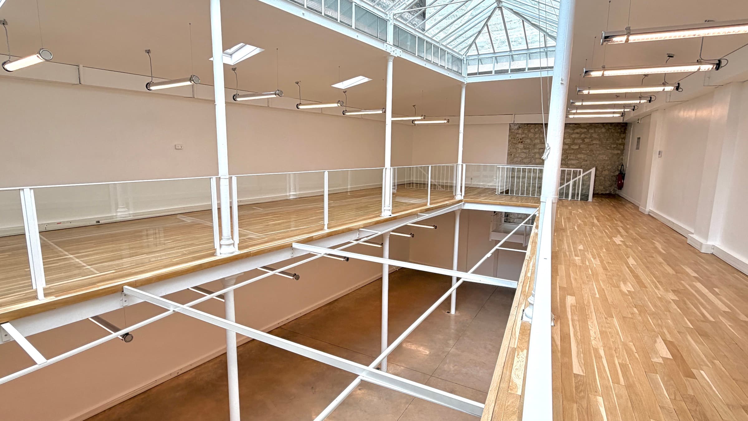 Coursive de la mezzanine en parquet le long de la trémie avec mur en pierre apparente