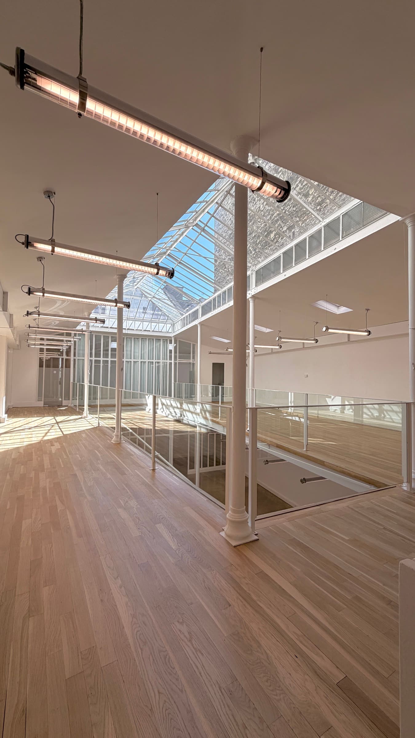 Plateau de la mezzanine en parquet avec suspensions tubes industriels et garde-corps en verre