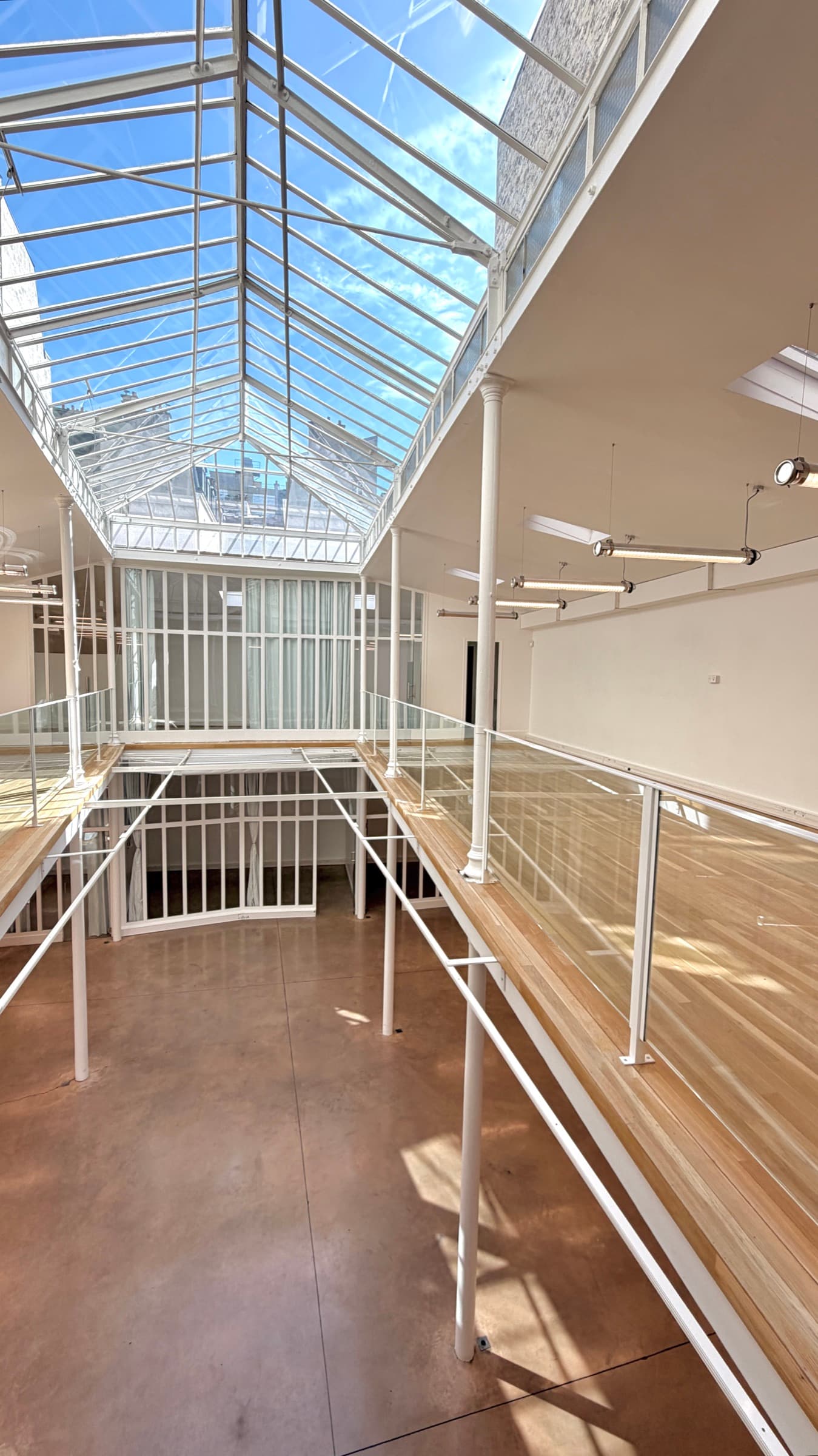 Coursive de la mezzanine en parquet et garde-corps blancs le long de la trémie