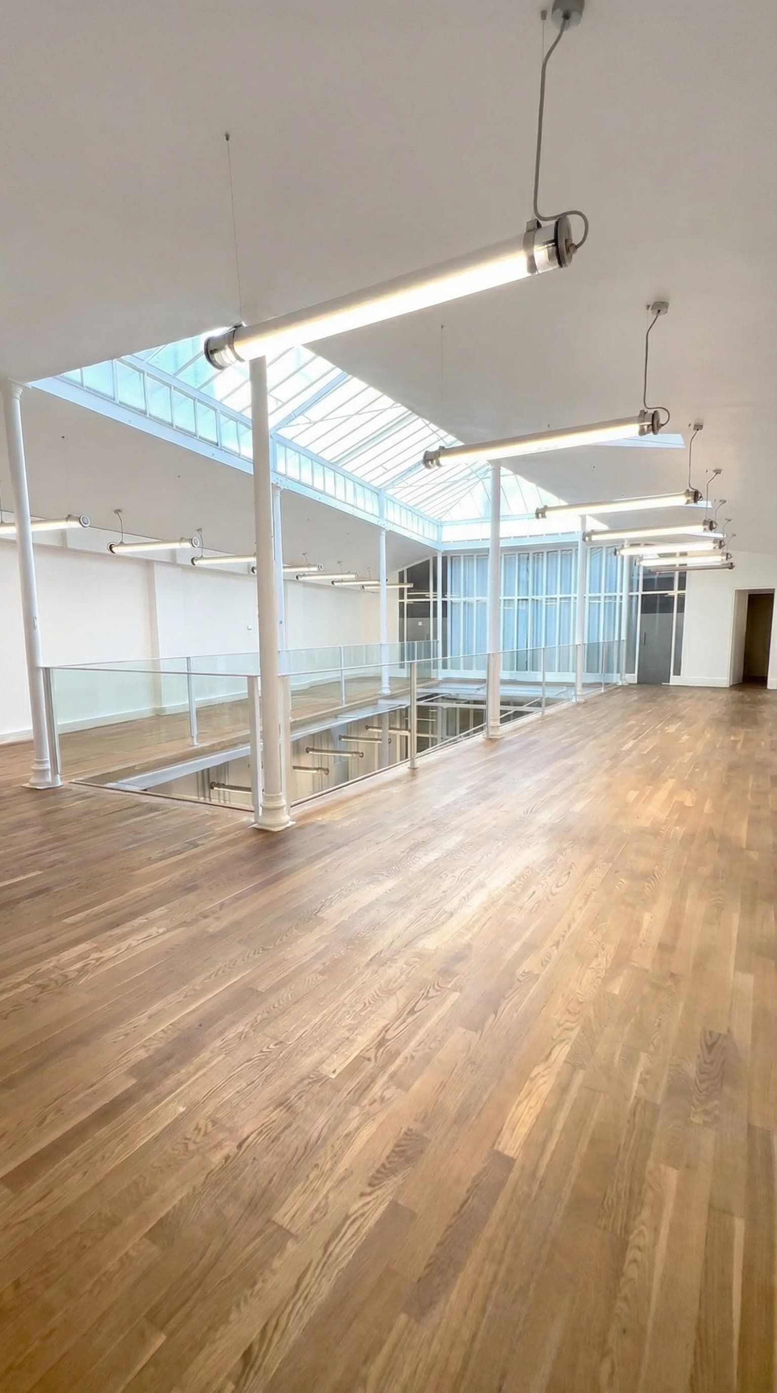 Mezzanine avec parquet chêne, colonnes et vue sur la verrière