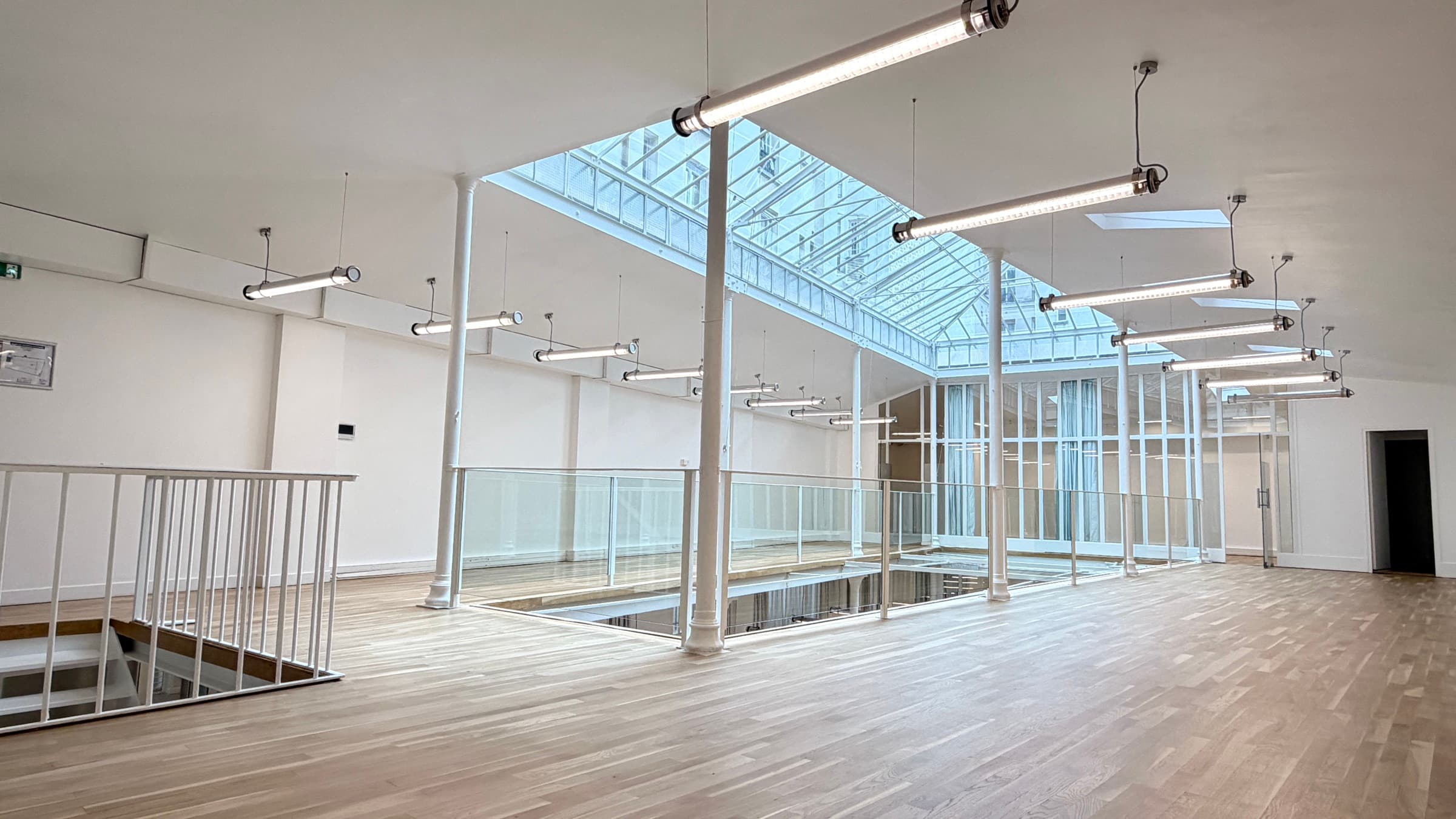 Mezzanine grand angle avec garde-corps vitré autour de la trémie, colonnes et verrière