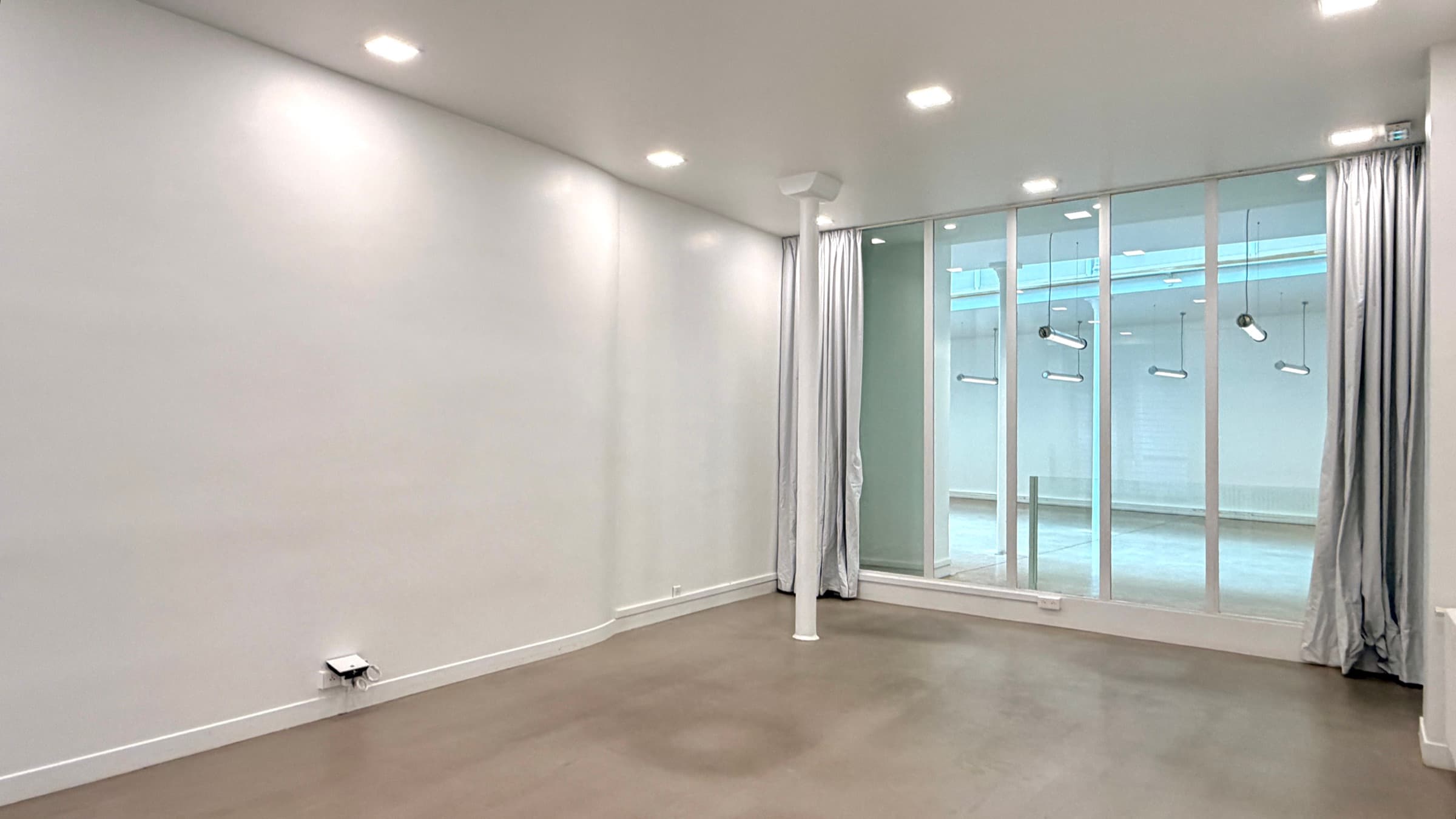 Salle vitrine sur rue du RDC avec spots encastrés et baie vitrée intérieure